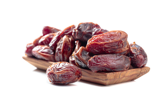 Dates in a wooden dish isolated on a white background.