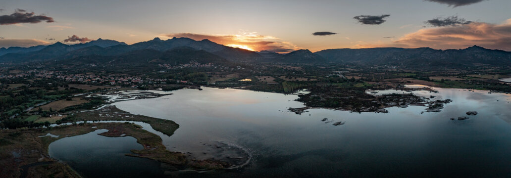 San Teodoro water lagoon with mountains along coastline in Sadinia Italy from above during sunset