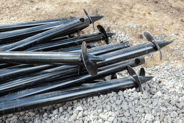 Screw piles stacked at construction site. Steel supports for foundation, building material