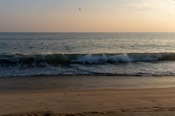 Small waves on a sandy beach on the coast of the pacific ocean at sunset on a summer day