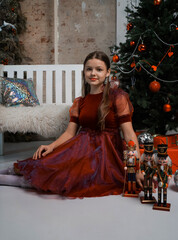 studio portrait of a girl in a red dress, near the Christmas tree