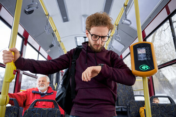 Portrait of ginger curly haired wearing glasses and wrist watch in aubergine sweater male rushing...