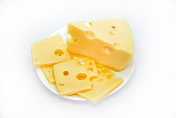 A large piece of cheese with holes on the plate. Chopped cheese and small slices on a white background. Juicy and delicious natural cheese. Cheese holes.