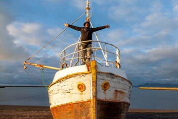 Middle-aged man playing captain on a boat stranded on an Icelandic beach