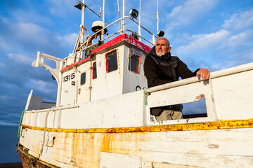 Middle-aged man playing captain on a boat stranded on an Icelandic beach