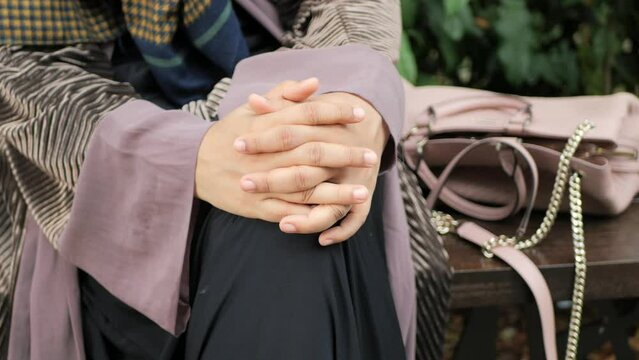 thoughtful muslim women sitting on park 