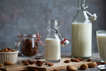 A bottle of almond milk with whole almonds on a table