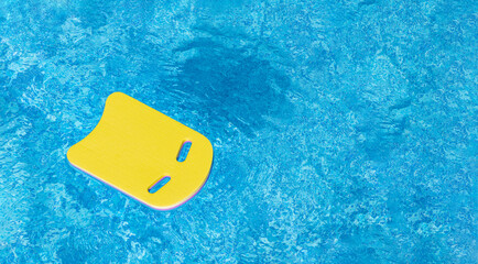 Safe pool training aid float foam board tool. Pink Swimming kickboard on blue water surface of swim...