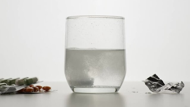 M&eacute;dicament soluble qui tombe dans un verre d'eau avec &eacute;claboussures