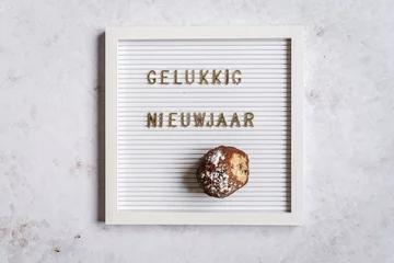 Fototapeten A white letterboard with Gelukkig Nieuwjaar (Dutch for Happy New Year) with one oliebol © Lizzy Komen