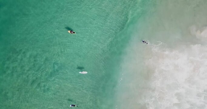 Surfers float over gentle waves in a slow aerial glide over the shoreline in San Diego