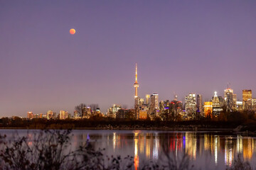 Fototapeta premium Total lunar eclipse full moon over the Toronto skyline