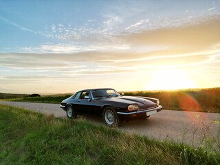 classic car in the field road at sunset