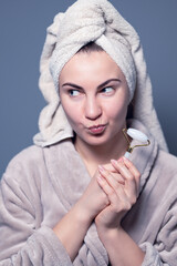 Obraz premium Women's beauty and spa. Beautiful woman using guasha jade stone roller massaging her face for a radiant complexion and healthy skin