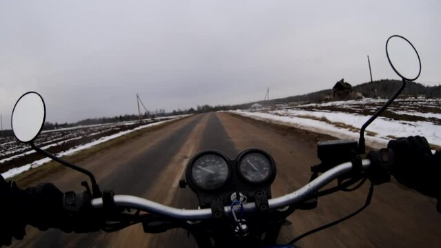 riding a motorcycle in winter on a snowy road in the cold from the first person.