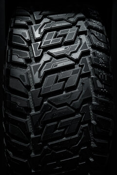 Close up picture of brand new black automobile Tyre texture on black background. Tread for crossovers and SUVs, off-road tires.     
