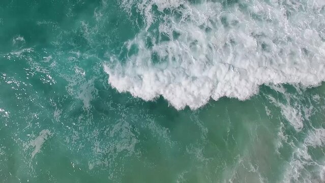 Atmospheric aerial above shorebirds flying over aqua ocean surf at the shoreline in Southern California