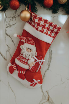 red Christmas stockings on fireplace decorated with Handmade Santa Claus. Minimal New Year season concept. Top view, flat lay on marble background. Composition sock hanging on white  wall.