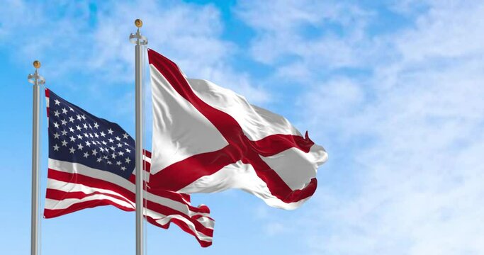 The flag of the state of Alabama waving alongside the national flag of the US on a sunny day