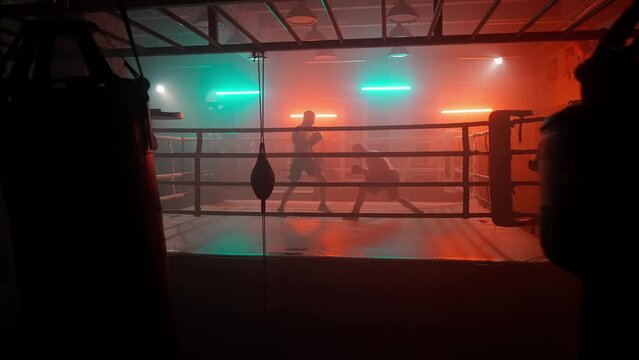 Boxer in the boxing gym. Bandages his hands. Sparring in the ring. Boxer jumping rope. Exercise with ropes. Round one. Fog in the ring. Zetsky sport. Beautiful backlight. World boxing champion.

