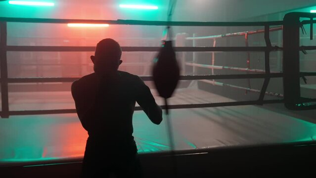 Boxer in the boxing gym. Bandages his hands. Sparring in the ring. Boxer jumping rope. Exercise with ropes. Round one. Fog in the ring. Zetsky sport. Beautiful backlight. World boxing champion.

