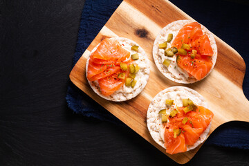 Healthy food non gluten Smoked Salmon canape Smoked salmon with rice cracker on wooden board on black slate stone