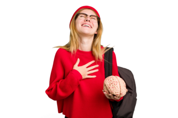 Young caucasian student woman holding a brain isolated laughs out loudly keeping hand on chest.