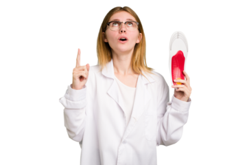 Young caucasian chiropodist woman holding an insoles for shoes isolated pointing upside with opened mouth.
