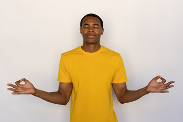 Relaxed young man meditating with closed eyes. Male African American model with brown eyes and...