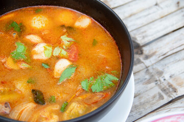 Top view of tom yam seafood soup in black bowl
