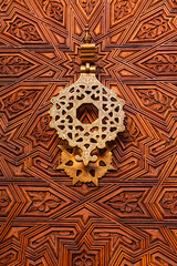 Puerta de estilo árabe de madera tallada con aldaba en bronce.