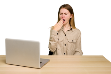 Young caucasian woman in a workplace working with a laptop isolated yawning showing a tired gesture covering mouth with hand.