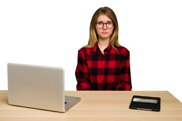 Young caucasian woman in a workplace working with a laptop isolated sad, serious face, feeling miserable and displeased.