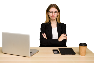 Young business caucasian woman working on her workplace cutout isolated frowning face in displeasure, keeps arms folded.