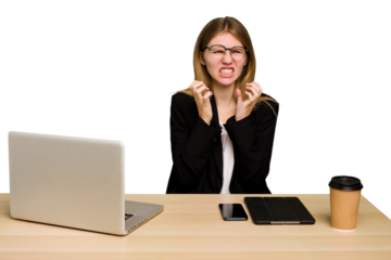 Young business caucasian woman working on her workplace cutout isolated upset screaming with tense hands.