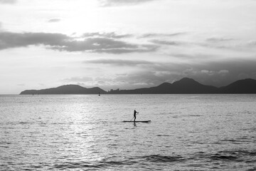 Girl practicing stand up paddle during the late afternoon in Santos bay photographed in black and white