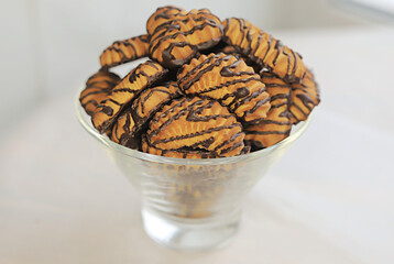 chocolate cookies in a transparent vase on a light background. place for text