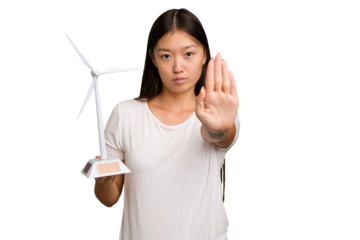 Young asian woman holding a small wind energy mill isolated standing with outstretched hand showing stop sign, preventing you.