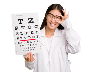 Young asian oculist woman holding a eye chart paper isolated excited keeping ok gesture on eye.
