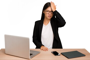 Young business asian woman sitting on a table isolated forgetting something, slapping forehead with palm and closing eyes.