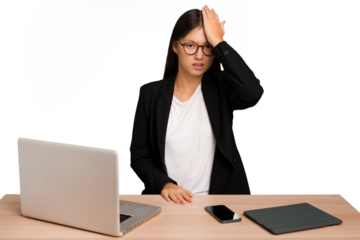 Young business asian woman sitting on a table isolated forgetting something, slapping forehead with palm and closing eyes.