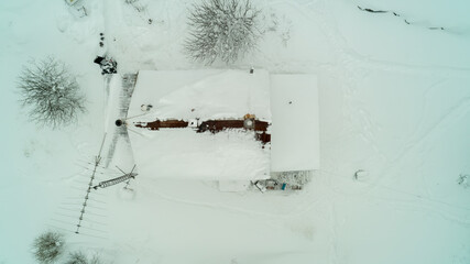 Aerial drone shot of the rooftop of a house covered in snow