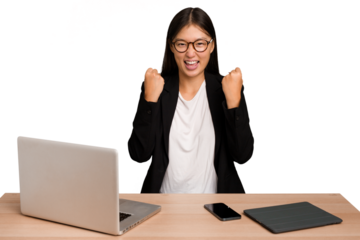 Young business asian woman sitting on a table isolated cheering carefree and excited. Victory concept.