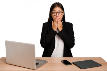 Young business asian woman sitting on a table isolated shocked, covering mouth with hands, anxious to discover something new.