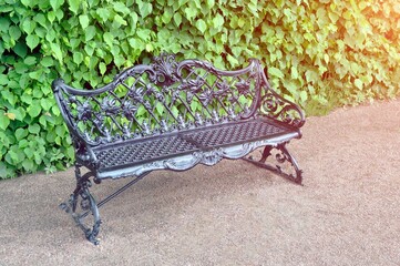 Openwork cast iron bench in the park in summer.