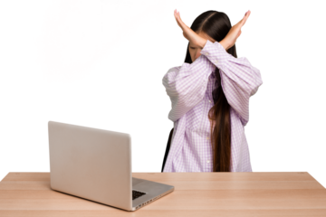 Young student asian woman in a workplace with a laptop isolated keeping two arms crossed, denial concept.