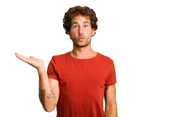 Young curly smart caucasian man cut out isolated impressed holding copy space on palm.