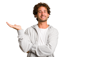 Young curly smart caucasian man cut out isolated showing a copy space on a palm and holding another hand on waist.