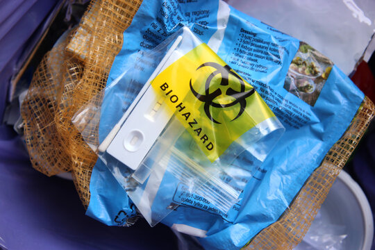 Used SARS Covid antigen test kit in the biohazard disposable bag thrown into a garbage can. 