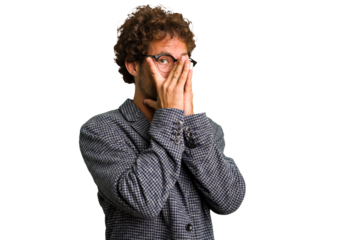 Young curly smart caucasian man cut out isolated blink through fingers frightened and nervous.